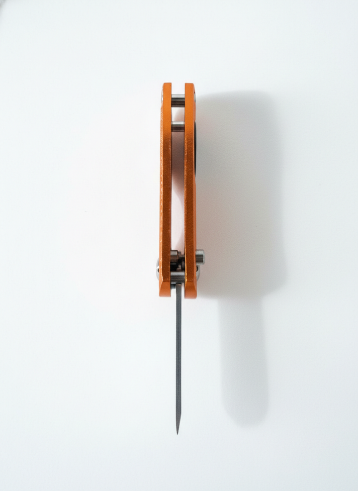 Limited edition divot tool in orange with a metal spike, viewed from above against a white background.
