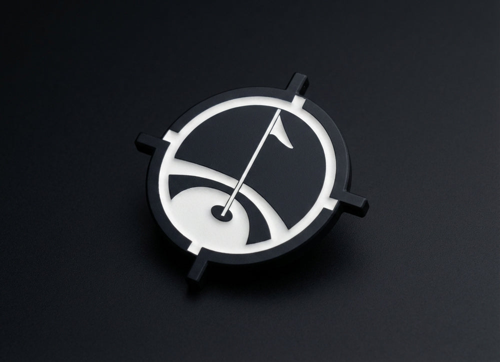 Matte black magnetic golf ball marker with precision white inlay on dark background