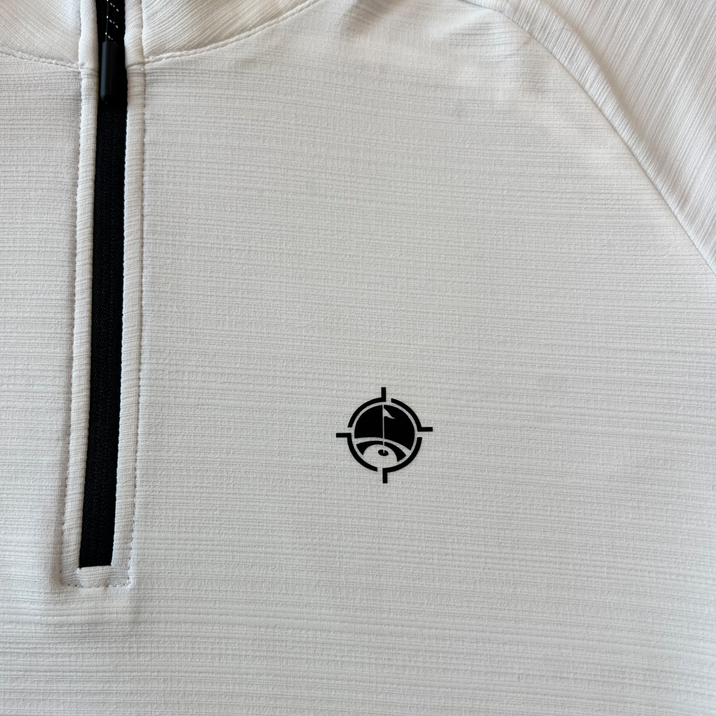 Close-up photograph of Aiming Fluid Golf’s logo on The Perfect Pullover t-shirt.