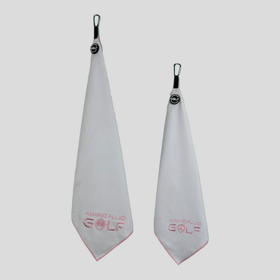 A tall boy and a stubby golf towel next to each other, in white and pink