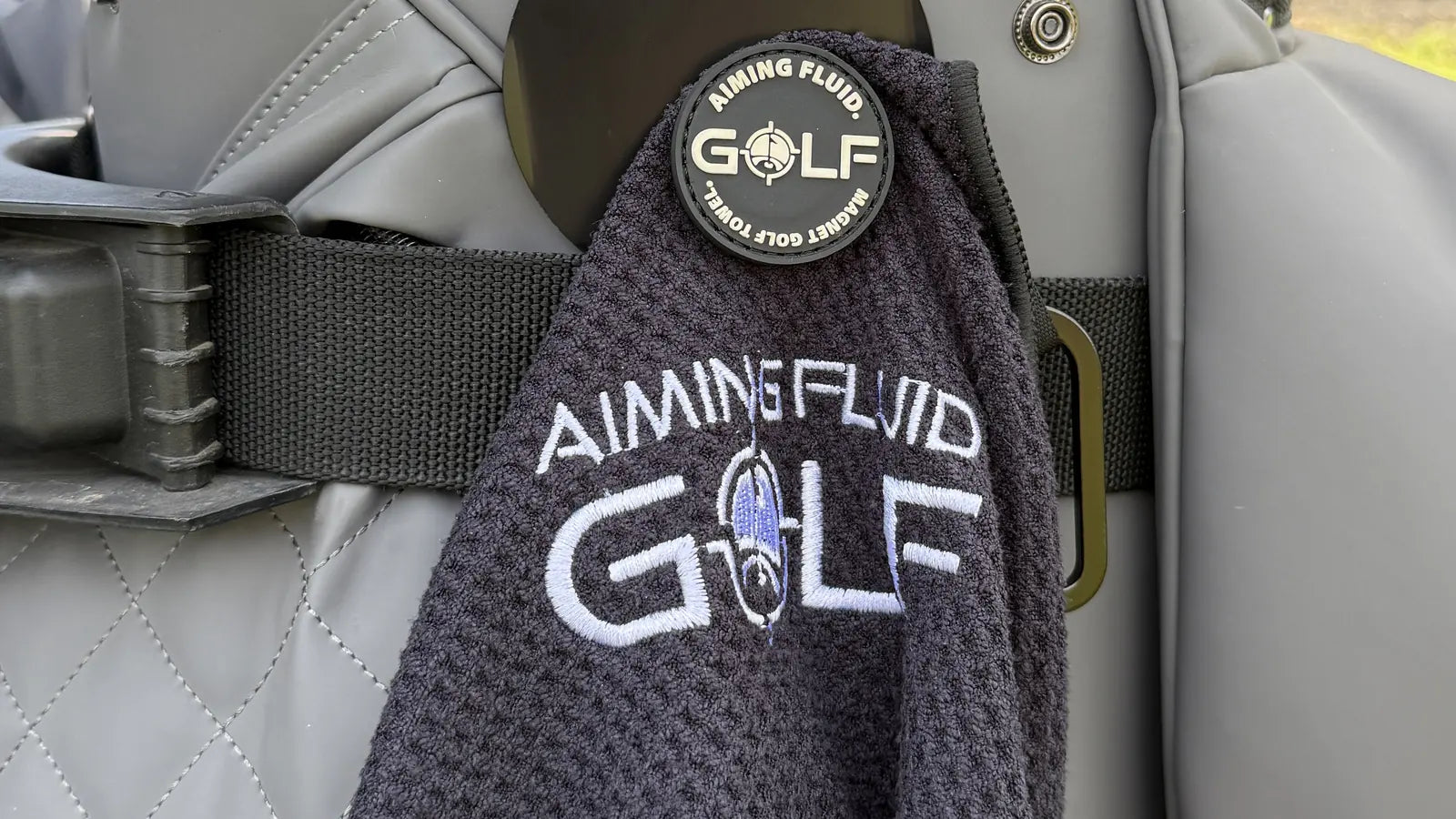Black Stubby towel hanging from its Landing Pad on a golf bag.